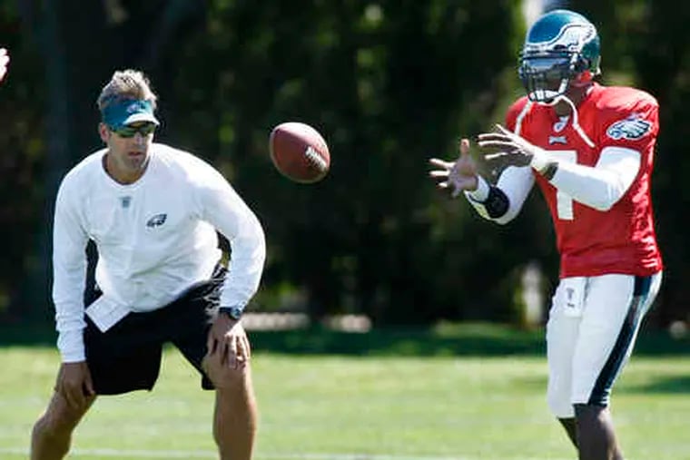 Michael Vick takes a practice snap as Eagles assistant coach Doug Pederson watches. Vick will start at Detroit on Sunday.