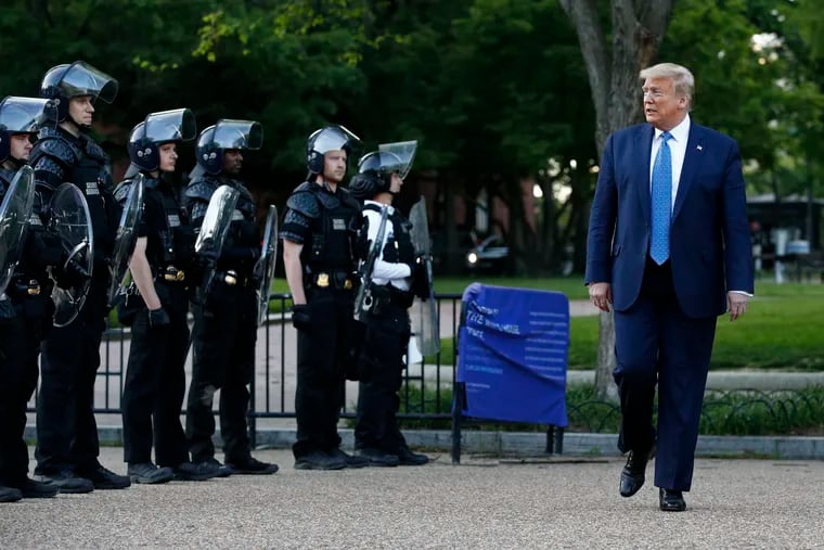 President Donald Trump walks past police in Lafayette Park after visiting outside St. John's Church across from the White House.