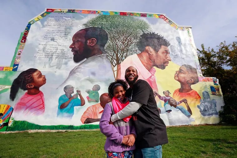 Standing in front of a mural they helped paint together, Shamira Williams, 10, greets her just-released dad, former inmate Graterford inmate Karim Williams.