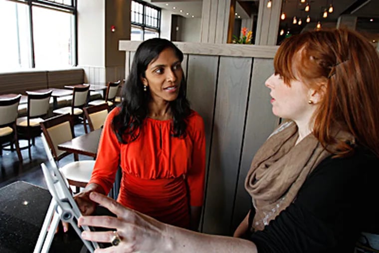 CityEats, a new online restaurant booking service, will compete with Open Table in Philadelphia. CityEats is backed by the Food Network and launched in Washington, DC. Narisa Wild, left, of CityEats, talks with Fish restaurant GM Nichole Berman, right, about their new service as she uses the table-management system on April 11, 2012. DAVID MAIALETTI  / Staff Photographer