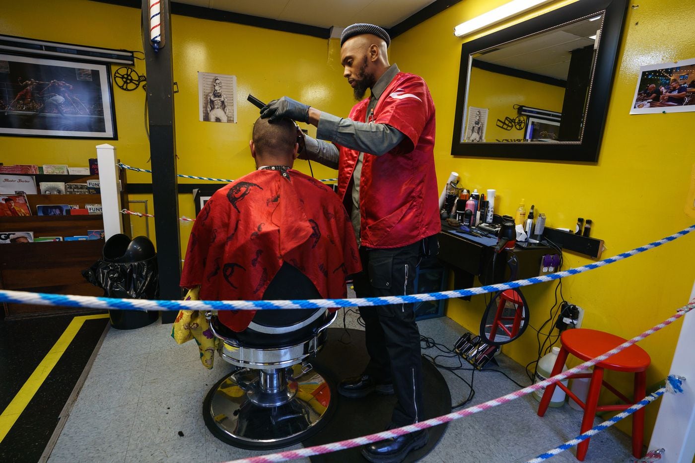 Jamel Workman cuts a customer's hair in his West Philadelphia barbershop. Workman has been repeatedly stopped by police in West Philly, with his car searched and no contraband found. 