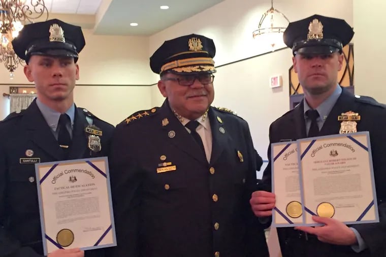 Officer Anthony Santulli (left) received a commendation from then-Commissioner Charles H. Ramsey in 2015 for his de-escalation tactics. Last weekend, Santulli allegedly bit a security guard at a rooftop bar in Center City.