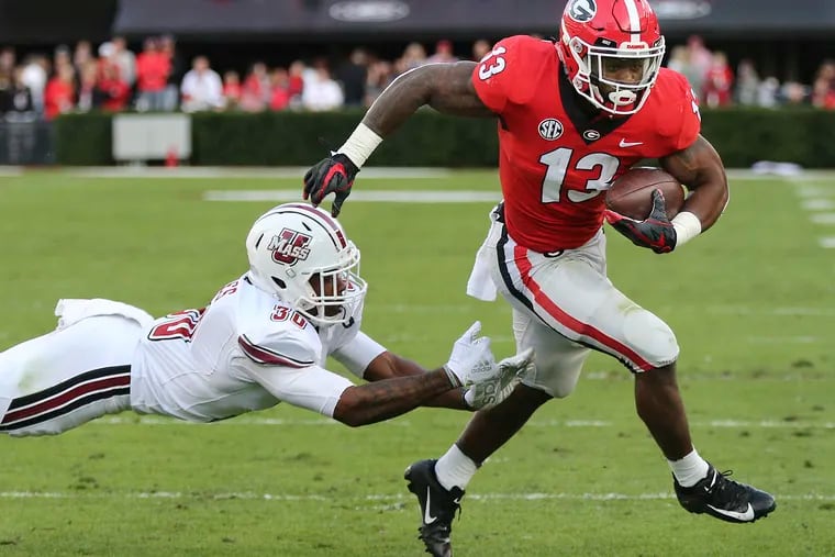 Georgia tailback Elijah Holyfield breaks away from Massachusetts safety Tyler Hayes for a touchdown during the first half of an NCAA college football game, Saturday, Nov. 17, 2018, in Athens, Ga. (Curtis Compton/Atlanta Journal-Constitution via AP)
