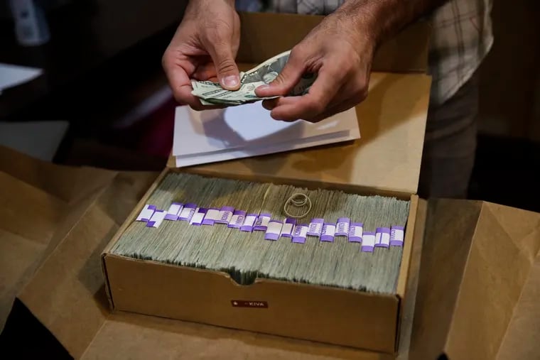 FILE - In this June 27, 2017 file photo, the proprietor of a medical marijuana dispensary prepares his monthly tax payment, over $40,000 in cash, at his Los Angeles store. Legislation that would provide federal protection for financial institutions that serve state-authorized marijuana and ancillary businesses has passed a U.S. House committee. The House Financial Services Committee voted 45-15 Thursday, March 28, 2019, to advance the bill after amending it to include provisions to provide a safe harbor for insurance companies and improve access of financial services to minority and women-owned cannabis businesses. (AP Photo/Jae C. Hong, File)