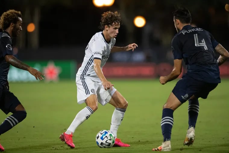 Brenden Aaronson dribblingbetween Sporting Kansas City's Gianluca Busio (left) and Roberto Puncec (right) during the first half.