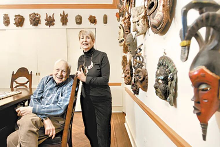 Stanley and Beverly Diamond sitting in the dining room of their home surrounded by tribal masks they have acquired over time in the travels. (Michael Bryant / Staff Photographer)