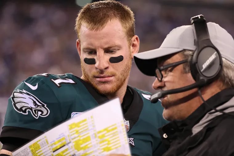 Eagle quarterback Carson Wentz looks over the choice of plays with head coach Doug Pederson during the team's Week 6 win over the Giants.
