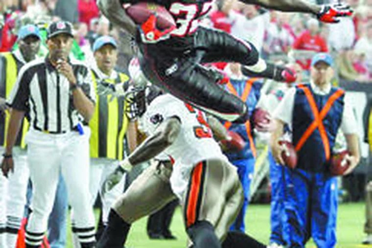 The Falcons&#0039; Jerious Norwood (32) goes up and over Buccaneers defenders Phillip Buchanon and Derrick Brooks but comes up just short of the goal line in the first quarter. Atlanta outlasted Tampa Bay in overtime. Story, E5.
