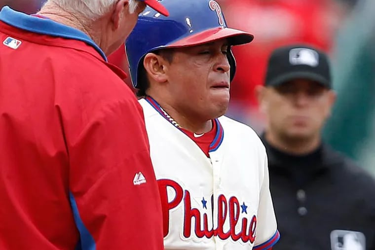 Charlie Manuel (left) checks on Carlos Ruiz after he injured himself running to third base during the second inning May 19, 2013. (David Maialetti/Staff Photographer)