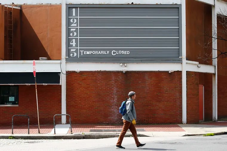 A pedestrian walks past a closed Landmark Ritz Five movie theater in Philadelphia on March 27, 2020.  The spread of the coronavirus has closed non-essential businesses.