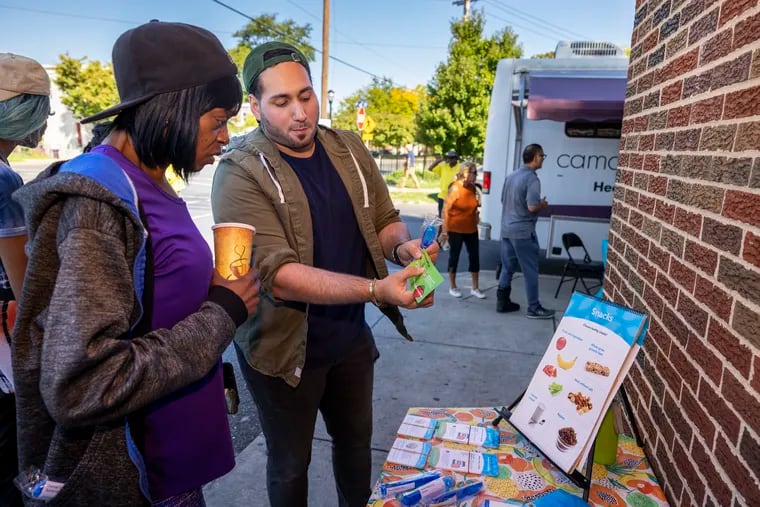 Jose "Junior" Placencia, Project Coordinator with The Food Trust makes a heart healthy presentation about better food choices to Andrea Hoagland. The Food Trust set up outside the 700 Pine Supermarket in Camden on Sept. 20.