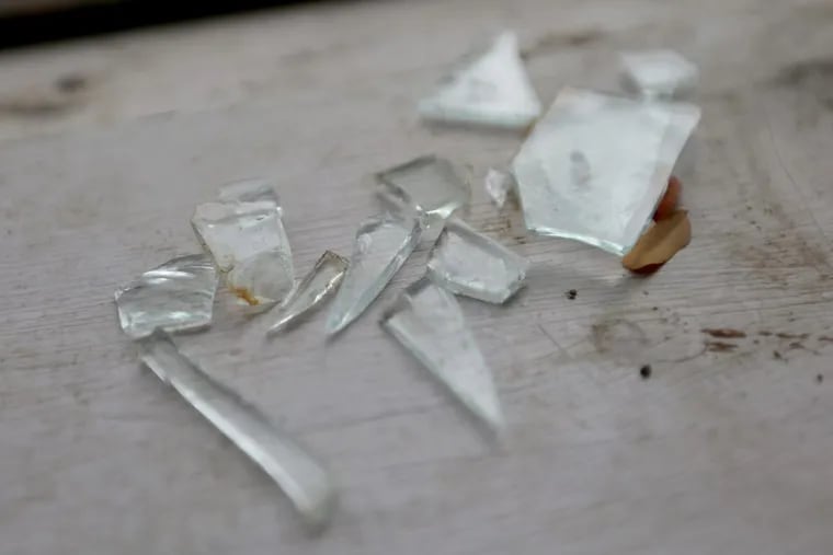 Pieces of glass rest on the windowsill of a home. The owner alleges drug dealers threw a Molotov cocktail through the window.