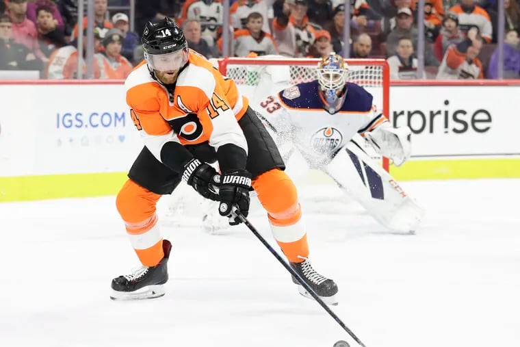 Center Sean Couturier reaches for the puck in front of Edmonton goaltender Cam Talbot in the Flyers' 5-4 overtime win Saturday. Couturier has 14 points in his last 10 games.