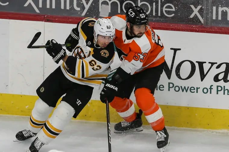 Shayne Gostisbehere checks the Bruins' Brad Marchand (left) during the third period.