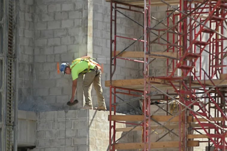 A construction worker uses a trowel to clear off mortar residue that had been scraped off the side of the Mormon Temple building construction on Wednesday afternoon, Aug. 27, 2014, in Philadelphia. (Michael Bryant / Staff Photographer)