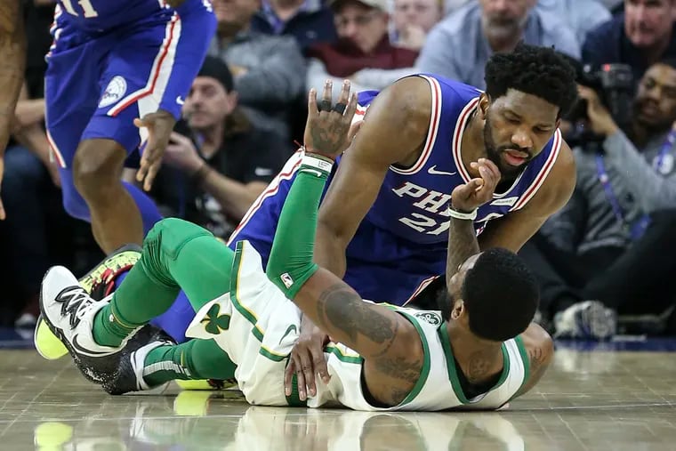 The Sixers' Joel Embiid lands on Boston's Kyrie Irving during the first quarter at the Wells Fargo Center on Wednesday night.