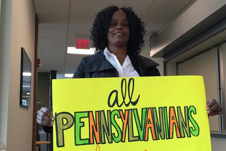 Tawanda Preston, a patient navigator at a Drexel University infectious diseases clinic, holds a sign saying "All Pennsylvanians Deserve Access" during a state advisory committee discussion in May 2016 in Mechanicsburg, Pa., about Medicaid guidelines that restrict coverage for expensive drugs that can effectively cure hepatitis C. The panel recommended coverage but the state has not announced a decision.