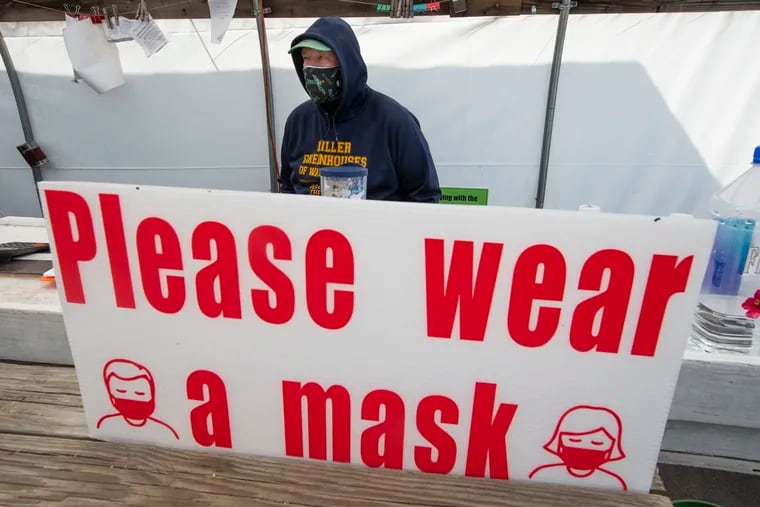 Ron Okarski stands by the checkout register at Miller’s Greenhouses of Wallingford last month with a reminder to wear a mask.