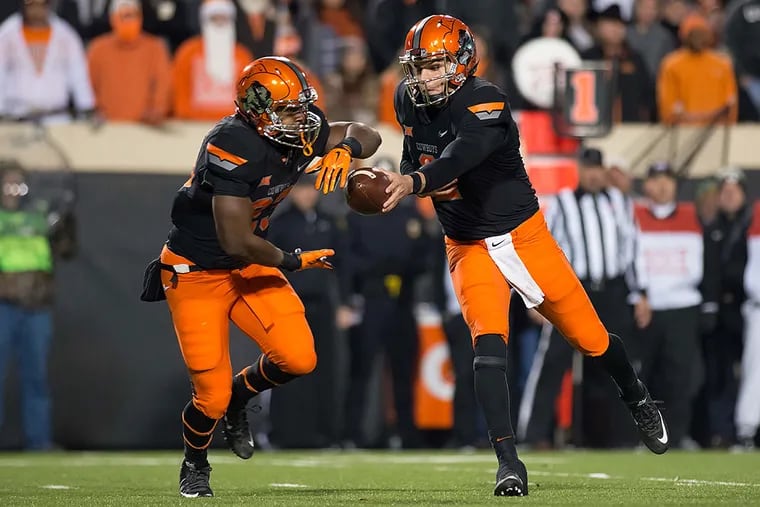 Oklahoma State Cowboys quarterback Mason Rudolph (2) hands of to Oklahoma State Cowboys running back Rennie Childs (23) against the Baylor Bears during the second half at Boone Pickens Stadium. Baylor won 45-35.