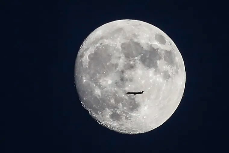 A commercial  airliner in front of the rising moon, as seen from Center City Monday night.
