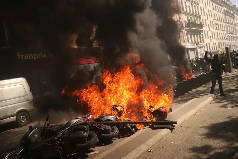 A set of motorbikes are set alight during a yellow vest demonstration in Paris, Saturday, April 20, 2019. French yellow vest protesters are marching anew to remind the government that rebuilding the fire-ravaged Notre Dame Cathedral isn't the only problem the nation needs to solve.