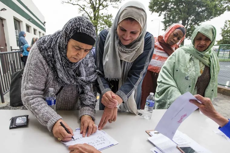 Ez-Zohra Baidouri (left), 73, from Morocco, registers to vote with the help of daughter Amina outside Masjid Al Furqan on Roosevelt Boulevard.