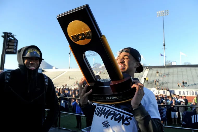 Sophomore guard Phil Booth lifts championship trophy as assistant coach Kyle Neptune looks on at rally at Villanova stadium on Tuesday.
.