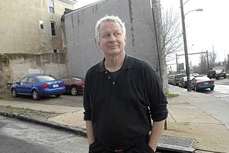 Author Joe Queenan stands in front of an empty lot in East Falls that used to house Len's Clothing, where he once worked. (April Saul / Inquirer)