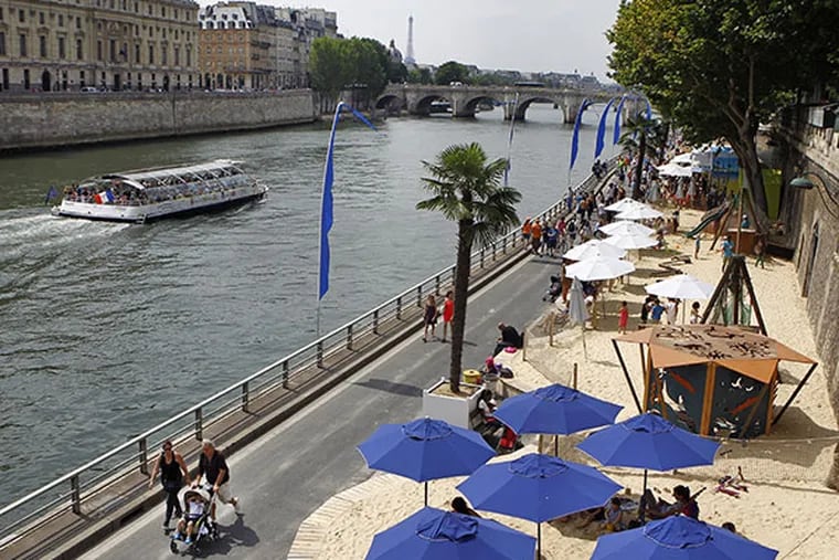 Tourists and Parisians take advantage of the Paris Plage event, an artificial beach set up on the right bank of the Seine river in Paris, with palm trees, outdoor showers and hammocks, Wednesday, July 23, 2014. (AP Photo/Remy de la Mauviniere)