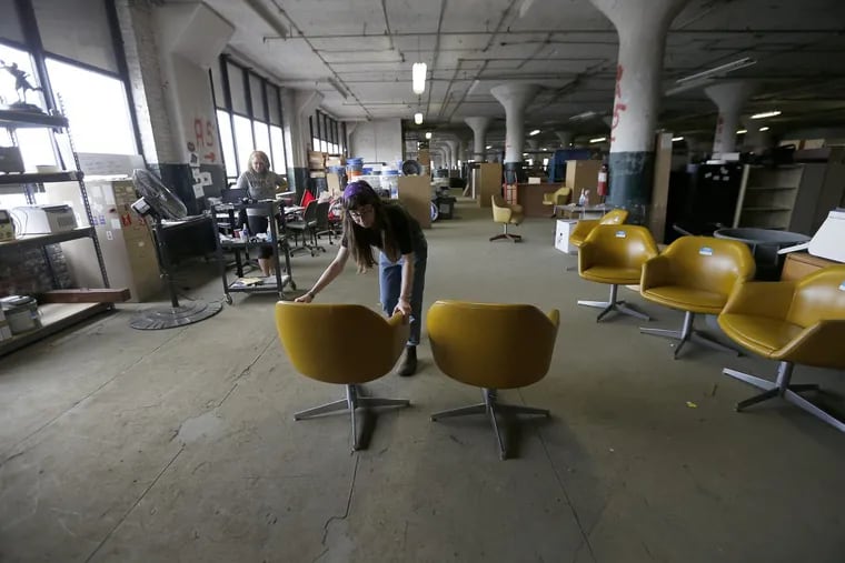 Temple University students Maric Kusinitz, right, and Chelsea Williams, left, log and photograph chairs at a Temple University warehouse. The university would throw out old furniture and equipment but now sells it.