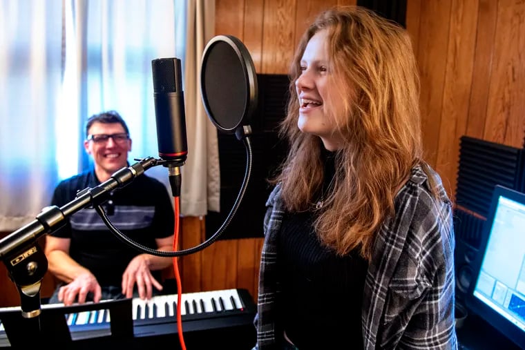 Stockton University biology professor Matthew Bonnan put science to music, recording an album, “Once Upon Deep Time.” He poses with his daughter Quinn, 17, who sang two of the songs, in their “home studio” in Hammonton.