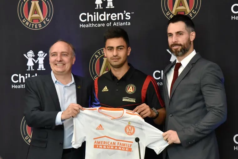 New Atlanta United MLS soccer team player Gonzalo "Pity" Martinez, center, the South American player of the year, is flanked by MLS Atlanta President Darren Eales, left, and Vice President and Technical Director Carlos Bocanegra, as they pose with a team jersey during a press conference in Marietta, Ga., Friday, Jan. 25, 2019.