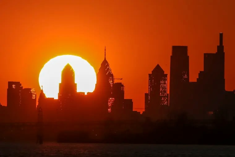 The sun sets behind the Philadelphia skyline as seen from the New Jersey side of the Delaware River.
