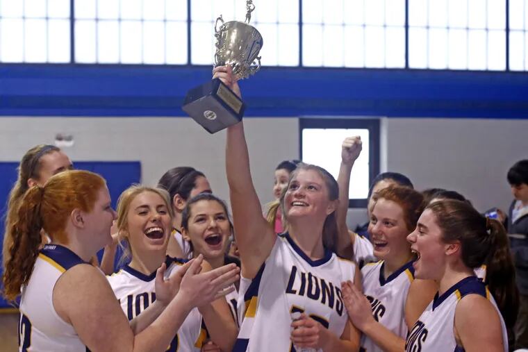 New Hope-Solebury players rejoice as senior Maggie Dougherty holds high the championship trophy after the Lions defeated Faith Christian in the Bicentennial Athletic League girls' basketball final at Holy Family University.