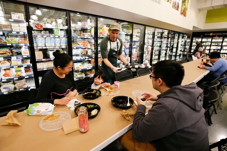 Weavers Way Co-op Ambler General Manager Jon Roesser hands out anniversary cake to Christopher Lee (right), Alexandra Lee and their daughter Lyla Lee at a table set up in the frozen aisle on Friday, January 25, 2019.  Weavers Way Co-op Ambler is celebrating one year of the Ò$4 FridaysÓ, $4 dinner they sell every week from 4 to 8 p.m. to customers who eat at the cafe or take out.