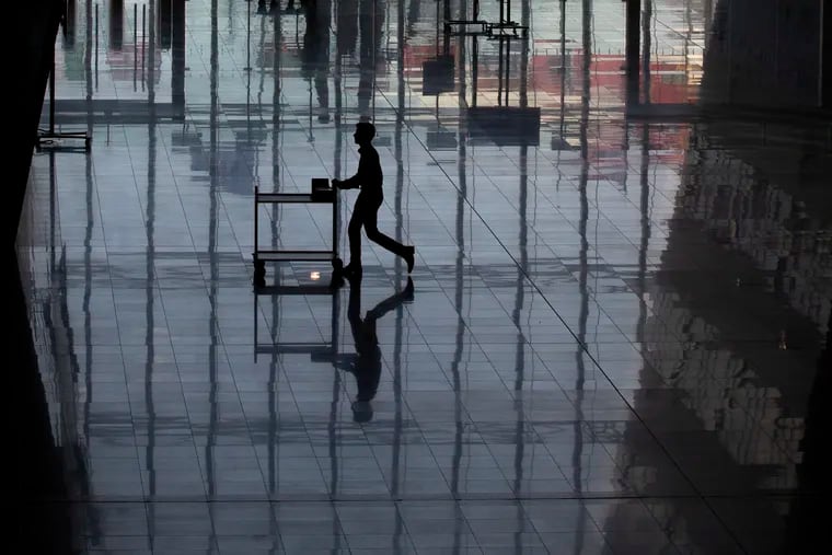 A man rolls a cart, reflected on the floor, at NATO headquarters in Brussels.