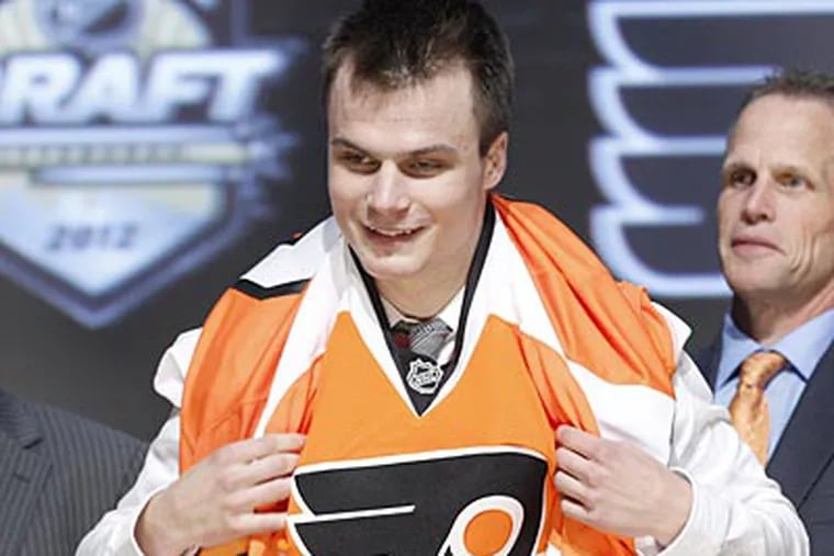Center Scott Laughton pulls on a Flyers jersey after the team drafted him with the 20th overall pick. (Keith Srakocic/AP)