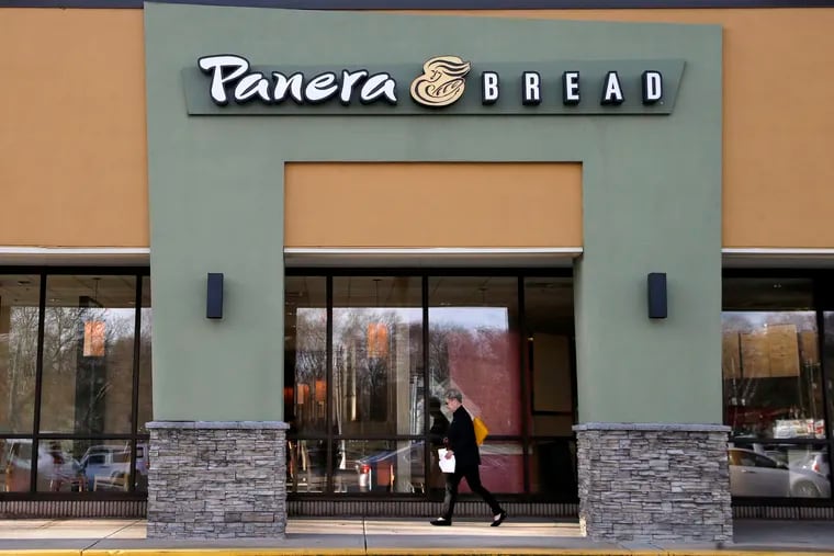 In this April 2017 file photo, a passer-by walks near an entrance to a Panera Bread restaurant in Natick, Mass.