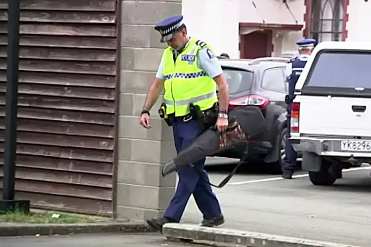 In this image made from video taken March 19, a police officer carries a gun voluntarily surrendered by a member of the public into the Masterton police station in Masterton, New Zealand.