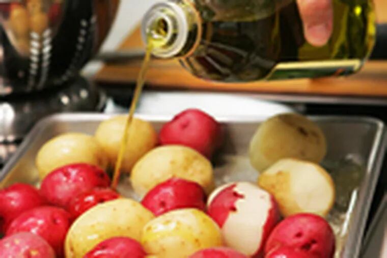A drizzle of olive oil is applied to the red-and-white potato dish about to be oven-roasted by Ann Hazan, who teaches basic cooking techniques at Foster&#0039;s.