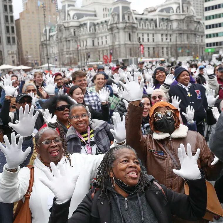 People put up their jazz hands with free white jazz gloves they received at the Philly Celebrates Jazz 2023 Kickoff Event in Love Park.
