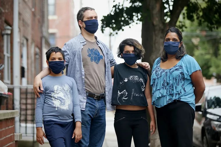 Jonathan Lipman (second from left) stands for a portrait with his wife, Aarati Kasturirangan (right), and children, Elijah Lipman (left), 9, and Asha Lipman, 12, outside their South Philadelphia home on Thursday, Sept. 10, 2020. Jonathan and his son have struggled with long-haul COVID-19, while his wife and daughter were briefly sick and have since recovered.