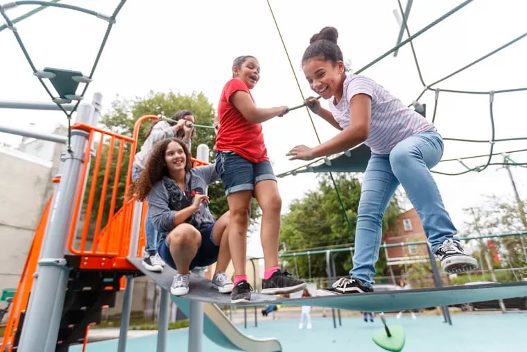 Judianis Guzman, 14, (right) leads Melanie Loaiza-Hernandez, 10, (center) and Grace Valentin, 11,  through the new playground area at the Fishtown Recreation Center.