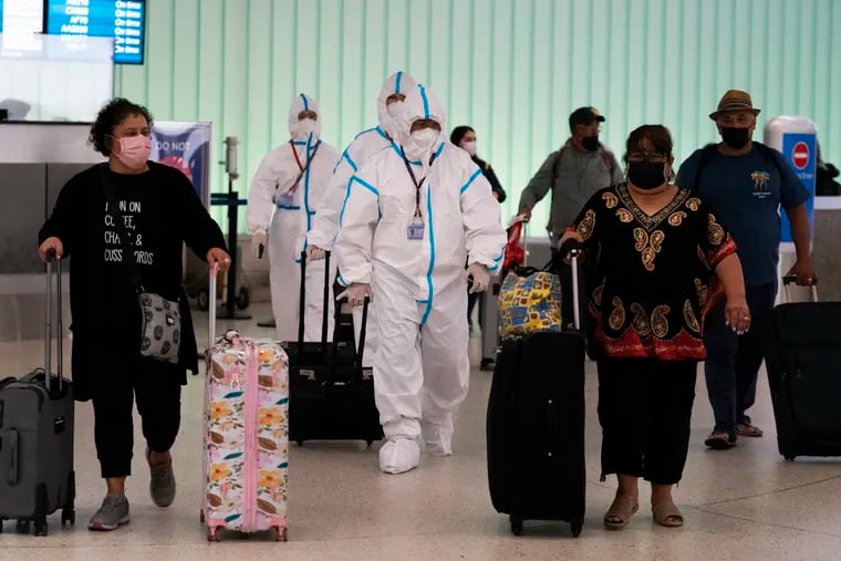 Air China flight crew members in hazmat suits walk through the arrivals area at the Los Angeles International Airport in Los Angeles, Tuesday, Nov. 30, 2021, days after South Africa reported a potentially dangerous new COVID-19 variant, omicron.