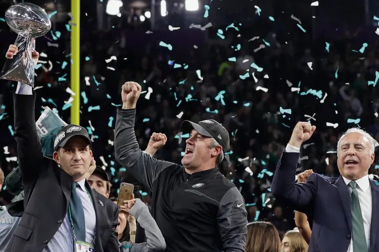 FILE – In this Feb. 4, 2018, file photo, Philadelphia Eagles general manager Howie Roseman, left, holds up the Vince Lombardi Trophy as he celebrates with head coach Doug Pederson, center, and owner Jeffrey Lurie after the NFL Super Bowl 52 football game against the New England Patriots, in Minneapolis. Owning the last pick in the first round of the NFL draft is a spot the Philadelphia Eagles want more often because it goes to the Super Bowl champions. Roseman is known for making moves. He's one of the most aggressive executives in the league. It's an organizational philosophy that's also reflected by coach Doug Pederson's playcalling. &quot;From our perspective, we're going to keep swinging,&quot; Roseman said. &quot;That starts with (owner) Jeffrey (Lurie). (AP Photo/Matt Slocum, File)