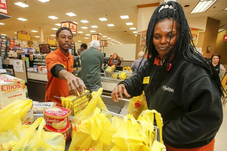 ShopRite employee LaShawna Bennett (right) helps bag items with Shakiel Taylor at ShopRite’s Roxborough store last week. Bennett and Taylor were both enrolled in a program that guaranteed jobs to ex-offenders who completed cashier training.