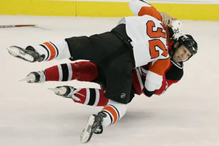 The Flyers&#0039; Riley Cote (32) tackles the Devils&#0039; Mike Rupp as they fight just two minutes into the game. A big second period helped New Jersey win.