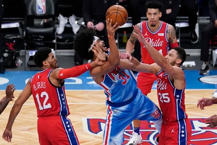 The Nets' Jarrett Allen (center) shoots between 76ers Ben Simmons (right) and Tobias Harris (left) on Thursday.