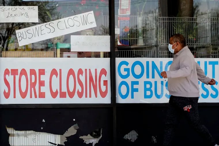 A man looks at signs of a closed store due to COVID-19 in Niles, Ill.