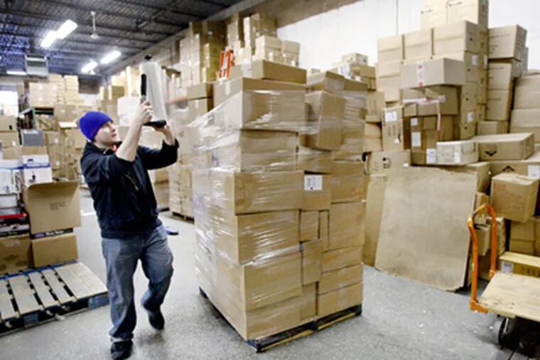 Kitchen Kapers shipping department supervisor Bill Bertole wraps a skid of Internet orders, to be picked up by UPS, in the firm's warehouse in Cherry Hill. (Elizabeth Robertson / Staff Photographer)